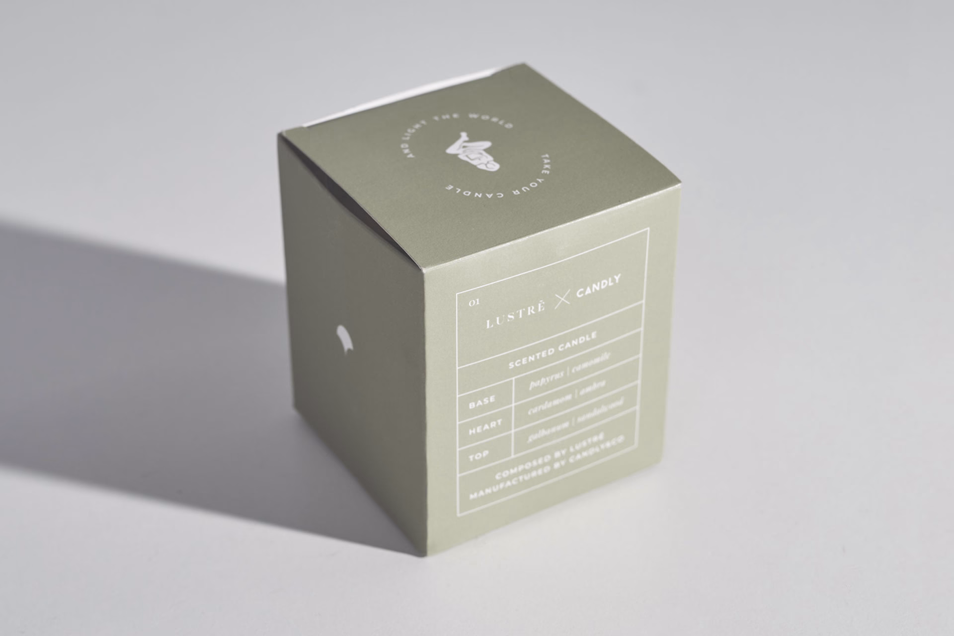 A pale green box with white text detailing a scented candle, partially visible against a light gray background.