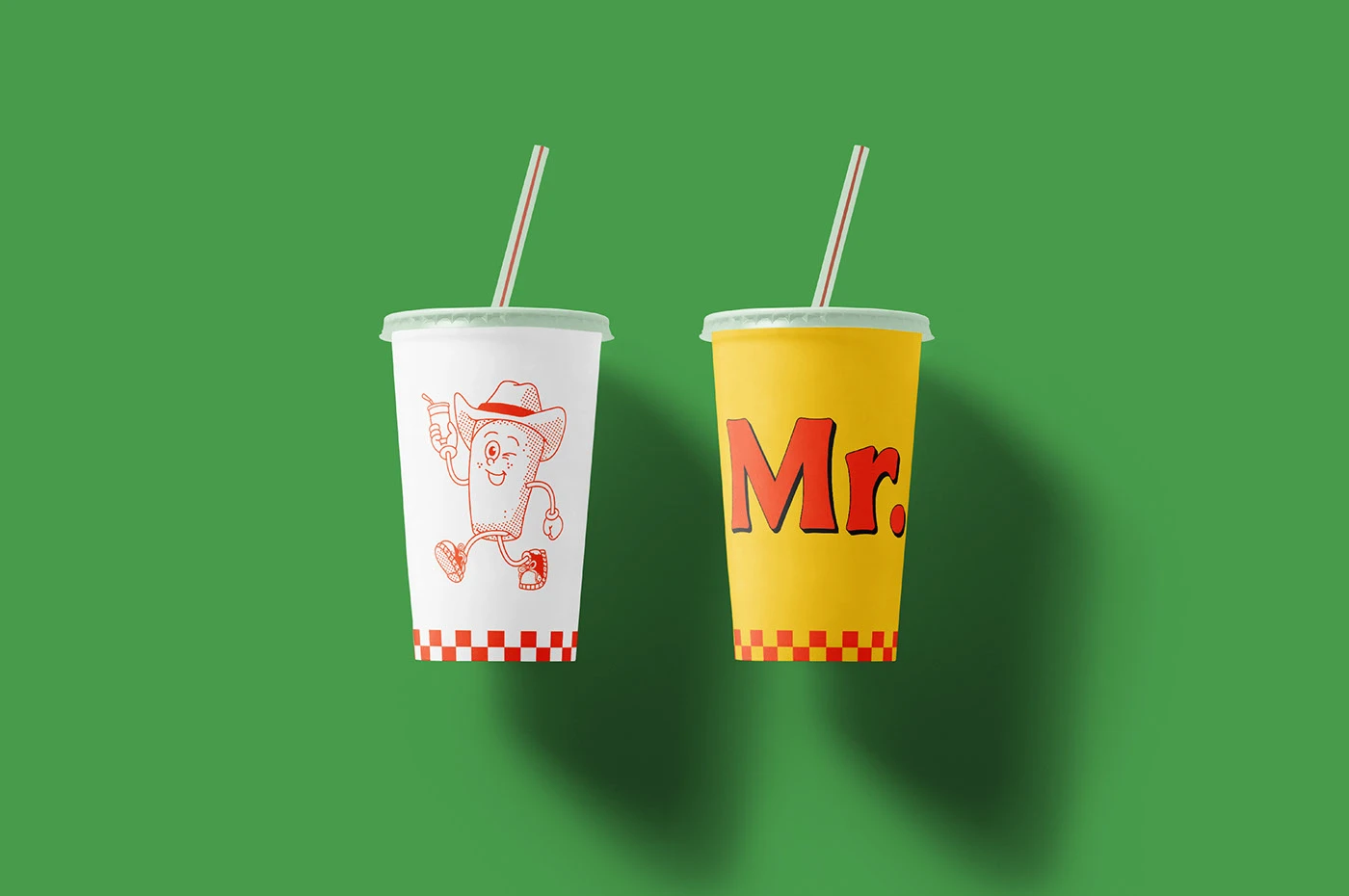 Two drink cups with red checkered patterns and straws on a green background.