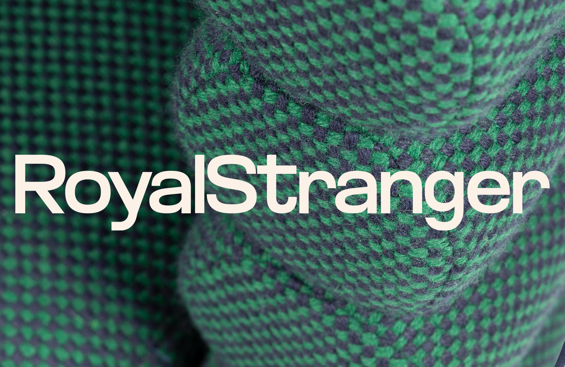 A close-up of textured green and dark fabric, featuring the bold text "RoyalStranger" prominently displayed.