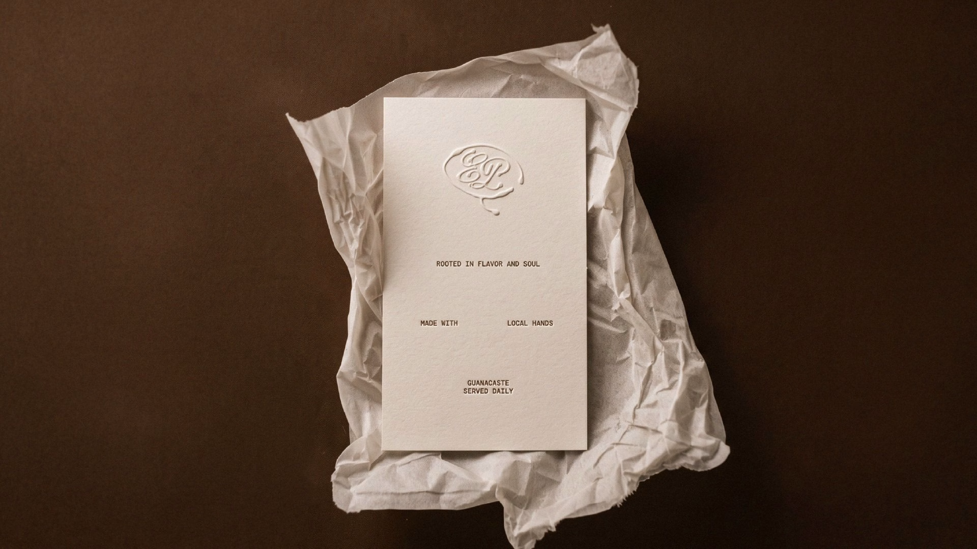 Embossed card featuring elegant typography on crumpled paper, representing El Puente's beach restaurant identity.