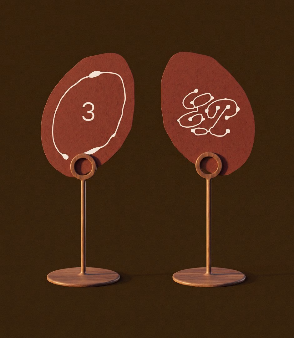 Two abstract, reddish-brown signs with white graphics, representing menu items for El Puente's beach restaurant identity.