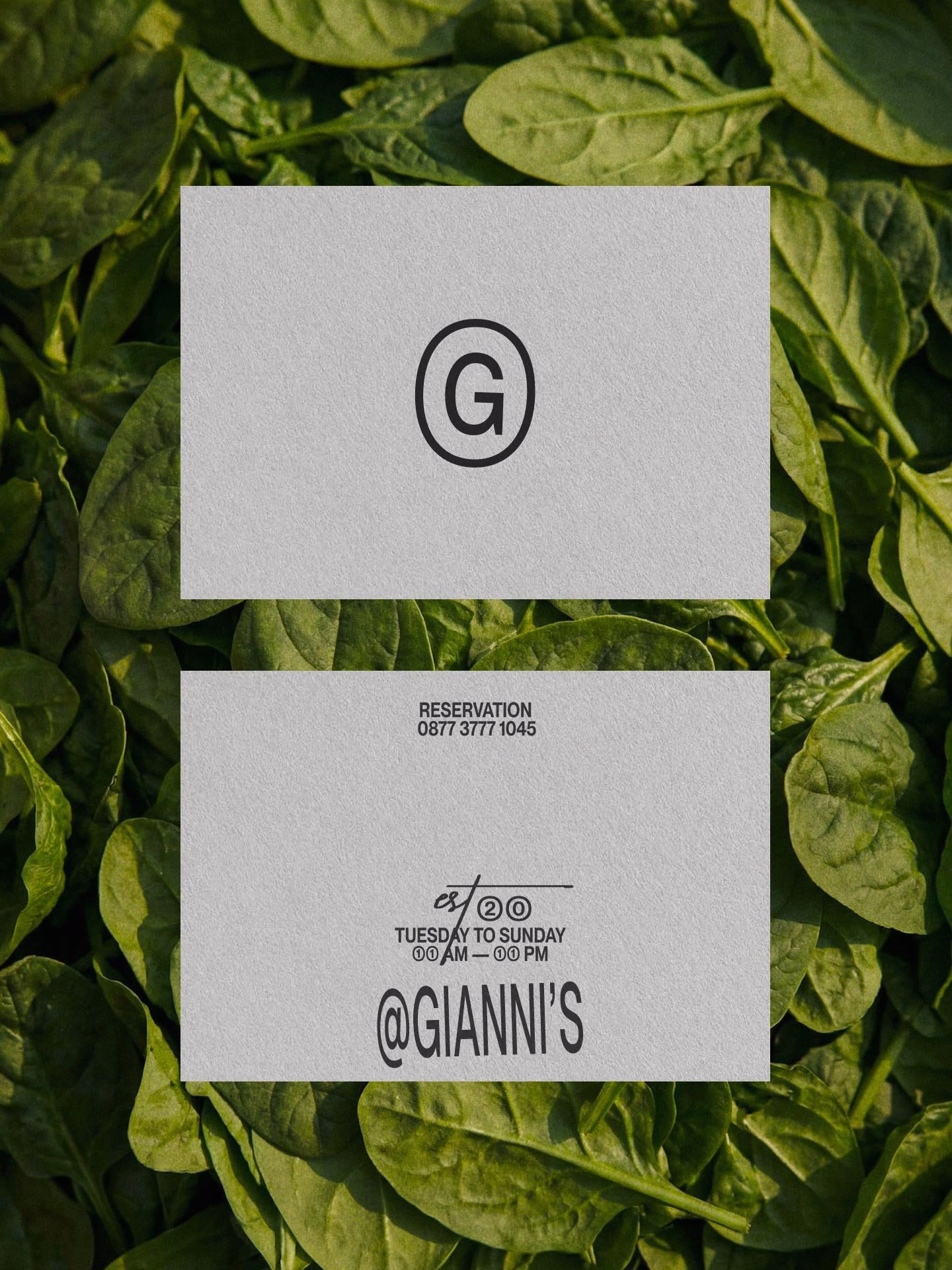 Business card design for Giannis resting on fresh spinach leaves, featuring a minimalist logo and elegant typography.