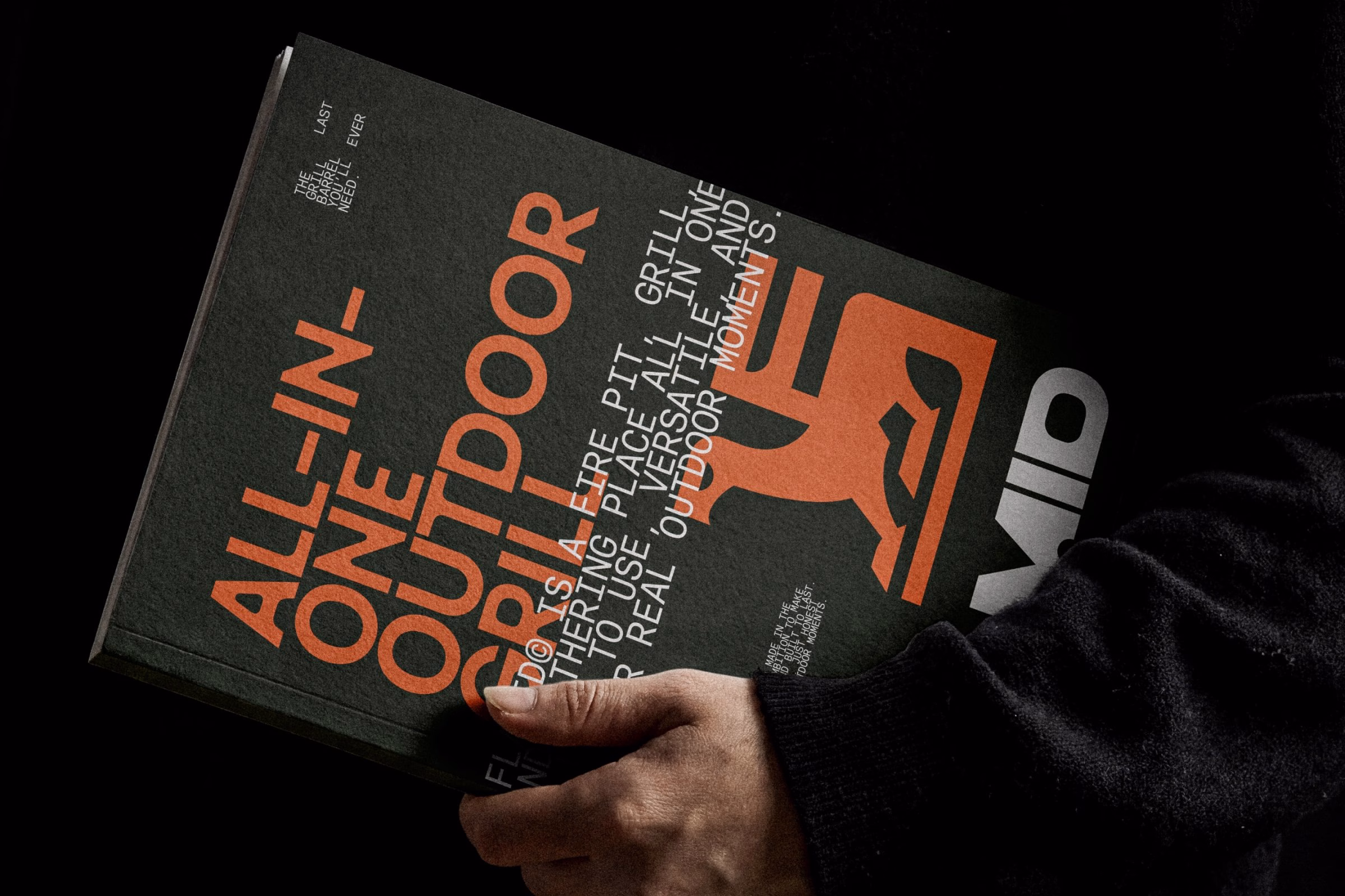 A hand holds a dark book cover featuring bold orange text and a bird-in-the-F symbol for Flamid’s design project.