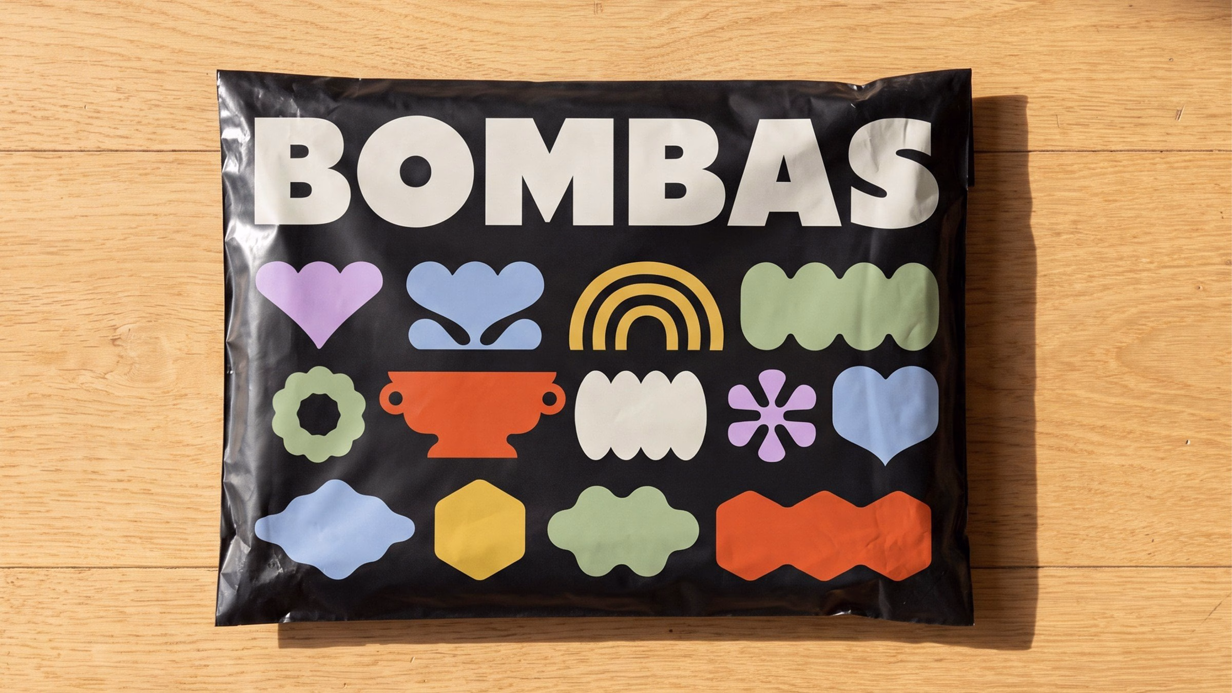 A black package features bold typography and colorful soft shapes representing Bombas' comfort brand identity.