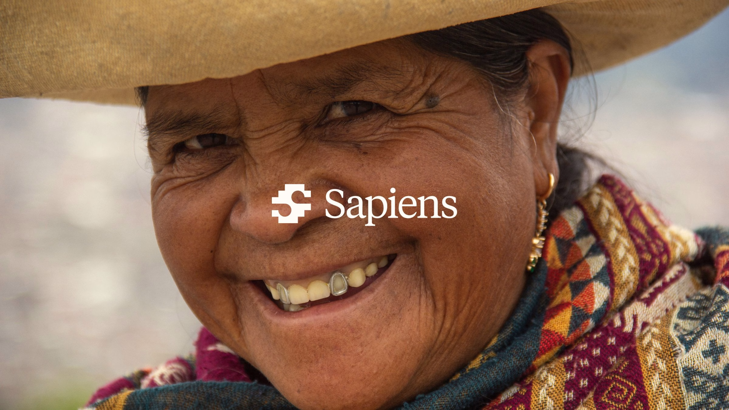 A smiling woman wearing a traditional woven scarf, with Sapiens branding prominently displayed across her face.