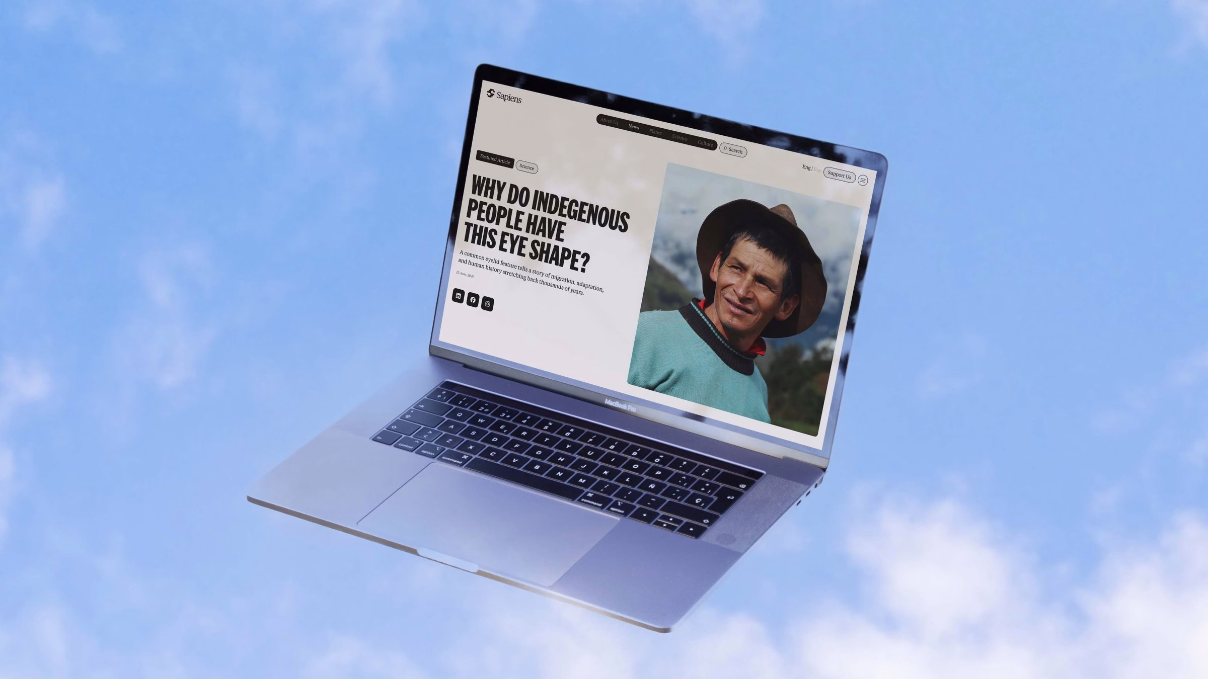 A laptop displays an article on indigenous eye shape, featuring bold typography and a portrait photograph against a blue sky.