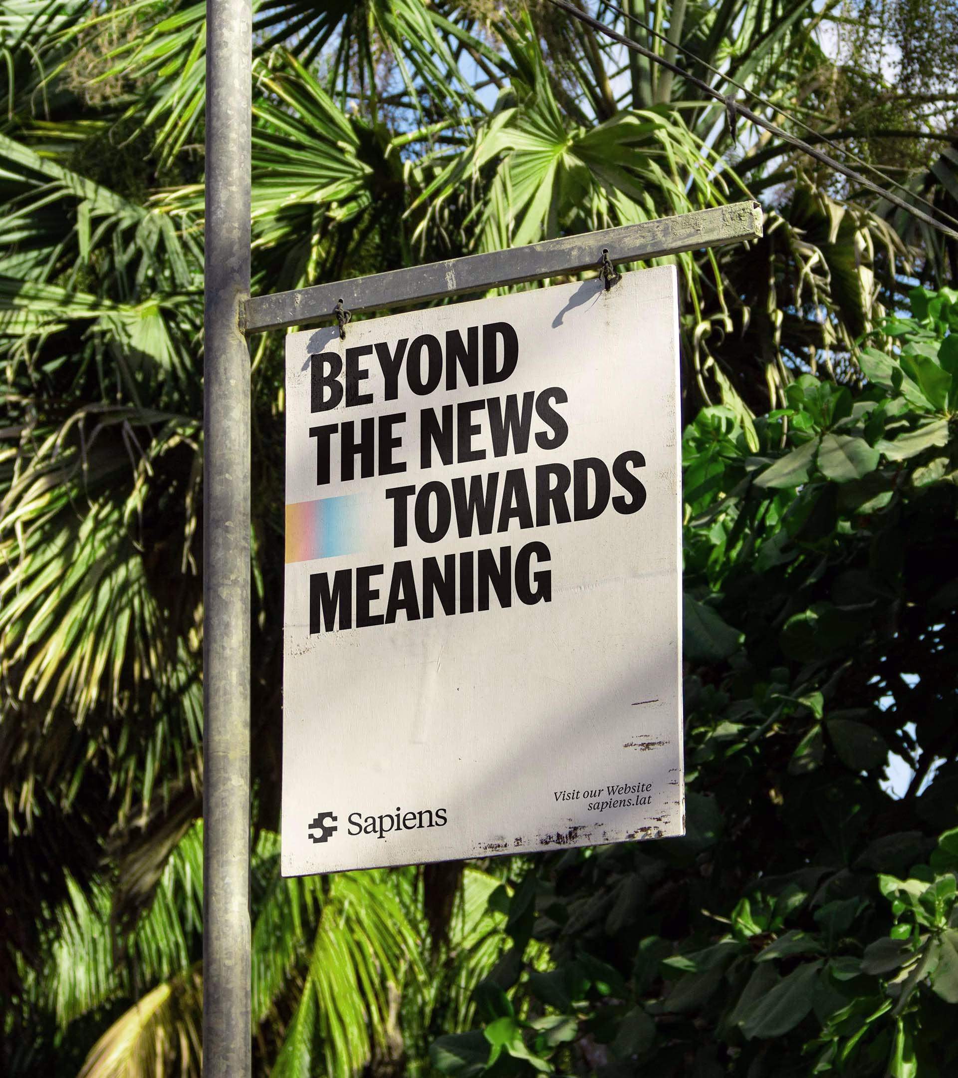 A poster featuring bold typography states "Beyond the news towards meaning," with greenery in the background.