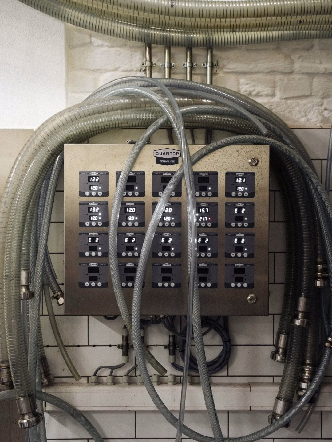 A metallic control panel with digital readouts, surrounded by thick, transparent hoses, depicting industrial design elements.