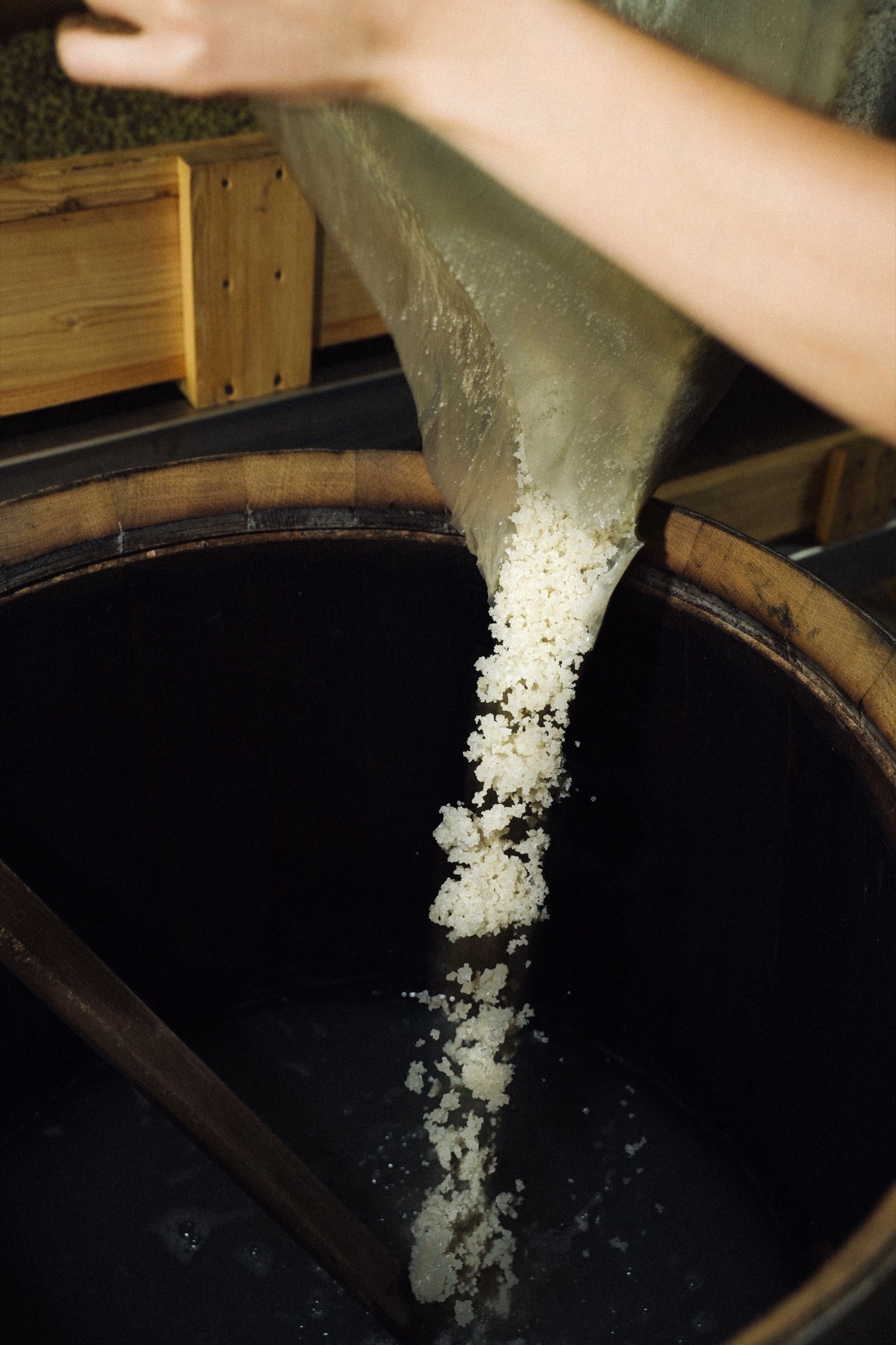 A hand pours white granules from a bag into a dark cylindrical container, part of Oraio's design-focused project.