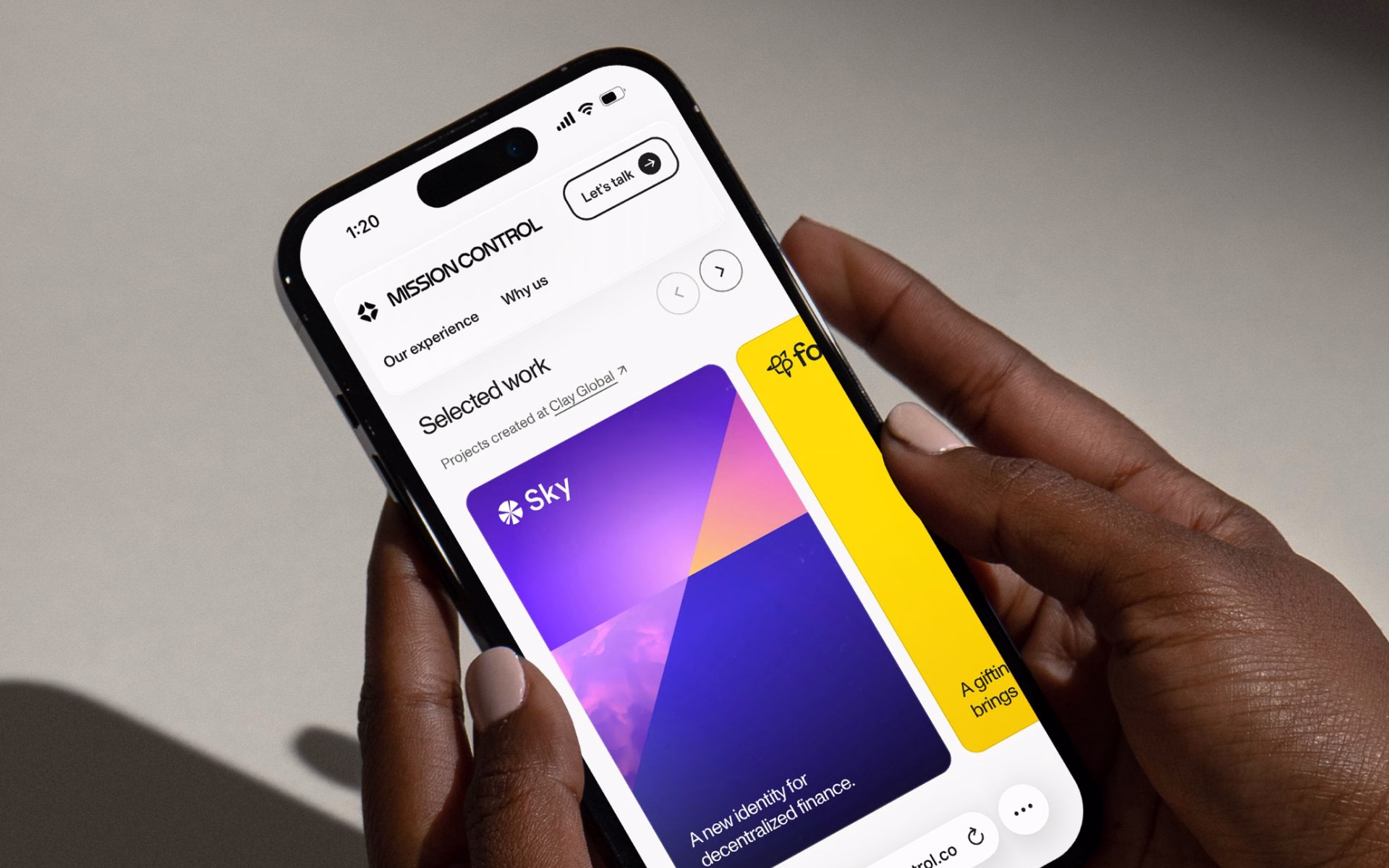 A hand holds a smartphone displaying the Mission Control website with dusk gradient visuals and modern typography.
