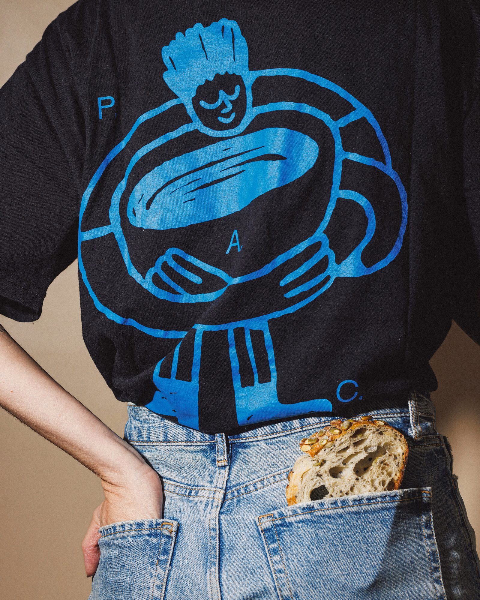 Black P.A.C. t-shirt with a large blue illustration of a figure hugging a cup