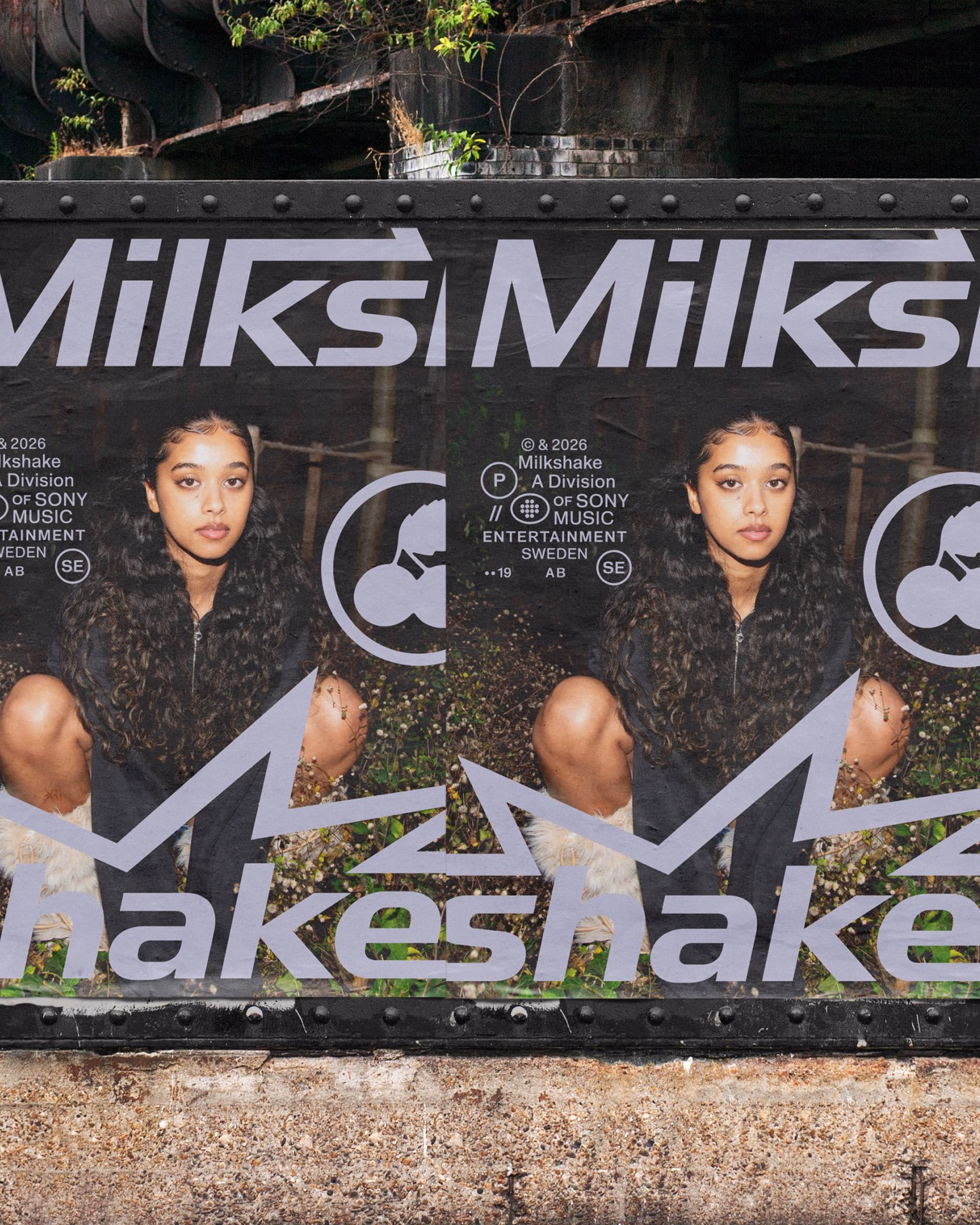 Poster featuring the text “Milkshake” in bold gray typography, with a young woman crouching in front of greenery.