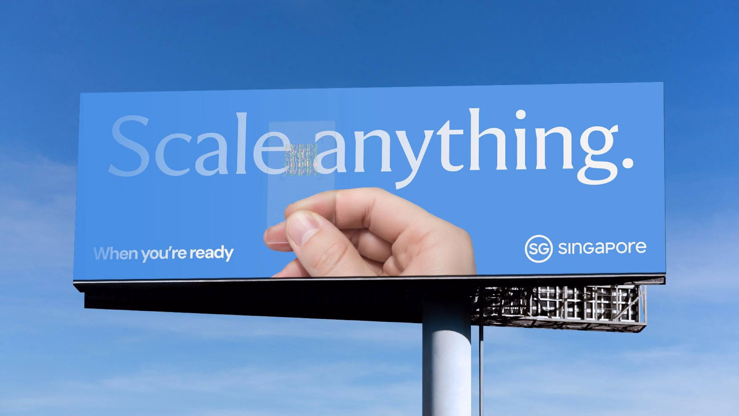 Billboard featuring a hand holding a clear object against a blue background, promoting Singapore's brand identity.