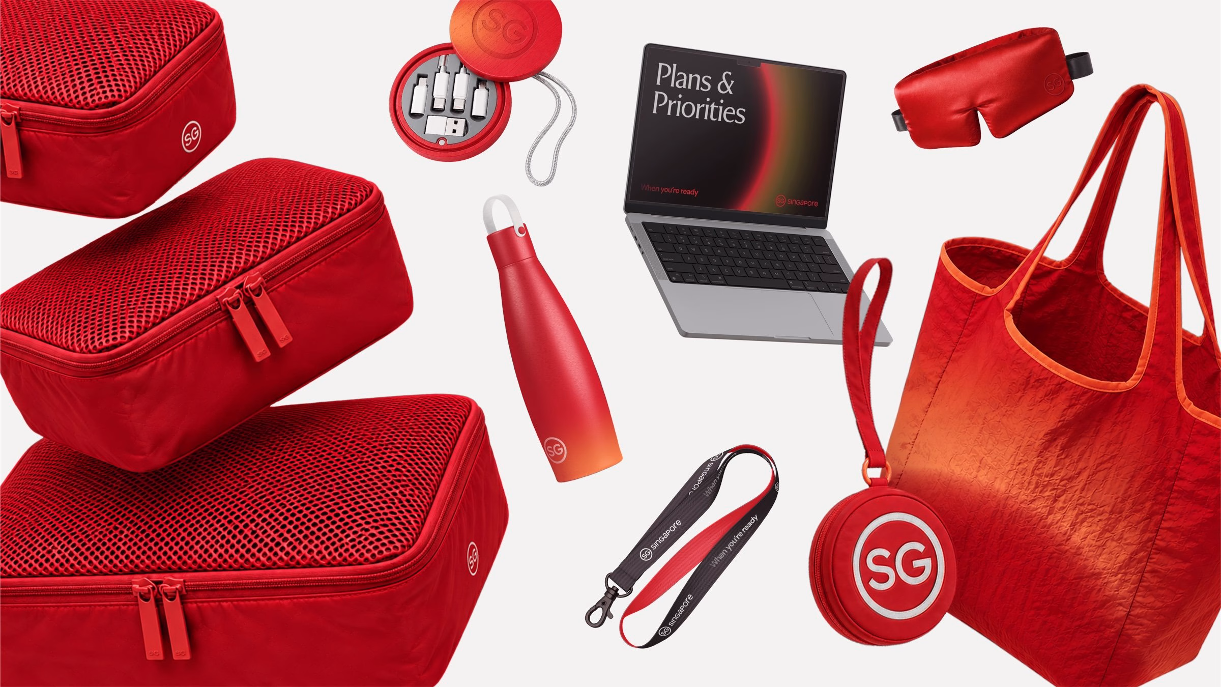 A collection of red branded products, including bags, a water bottle, and a laptop, showcasing vibrant textures and forms.
