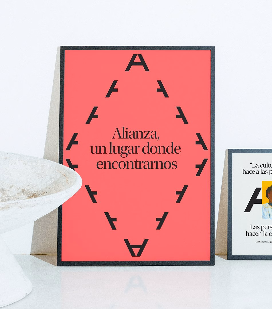 A coral poster featuring the word "Alianza" in bold typography, highlighted by a triangular arrangement of black letters.