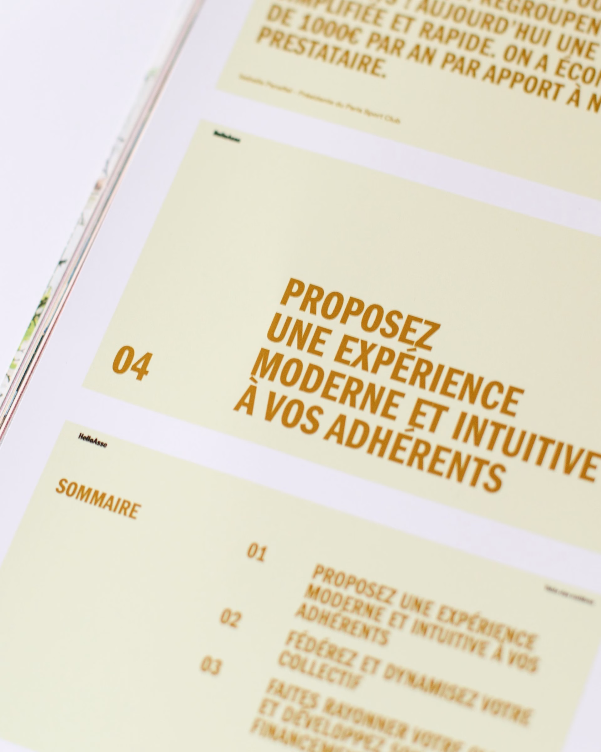 A close-up of printed pages featuring bold typography in brown on a light yellow background, showcasing HelloAsso's brand identity.