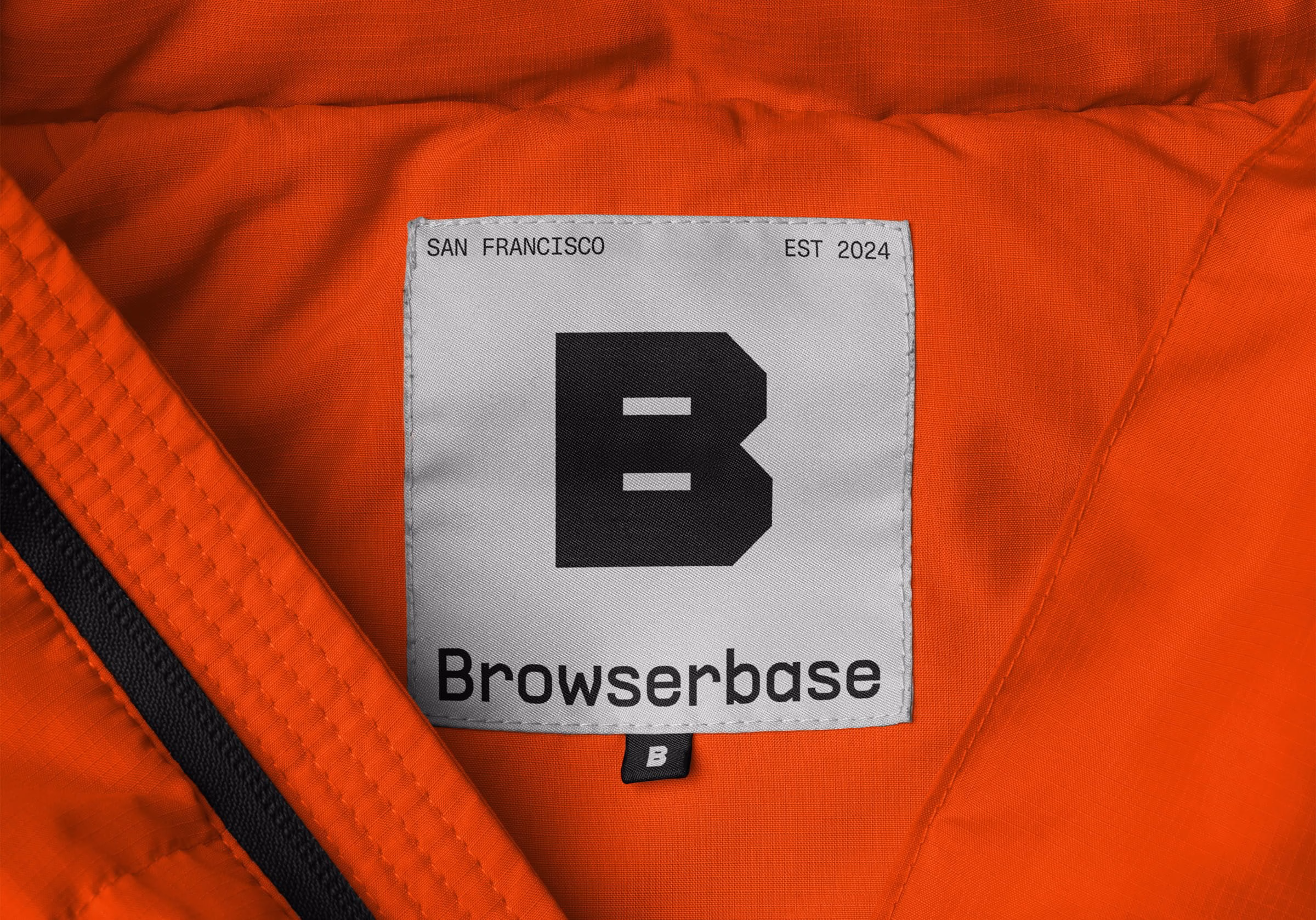 A close-up of a gray label featuring a bold 'B' logo and the text "Browserbase," set against bright orange fabric.