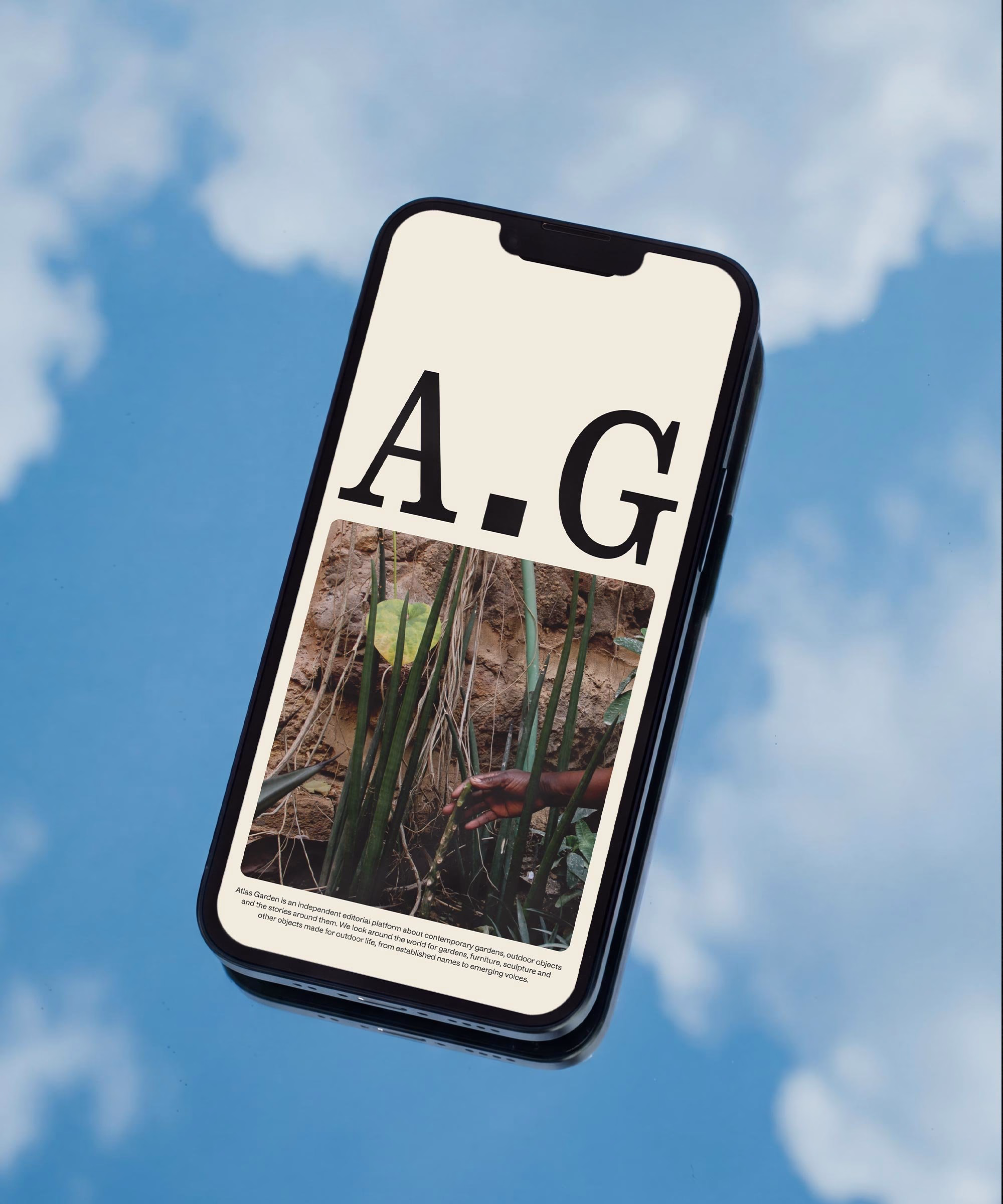 A smartphone displays an editorial design for Atlas Garden with large typography and a hand reaching towards plants.