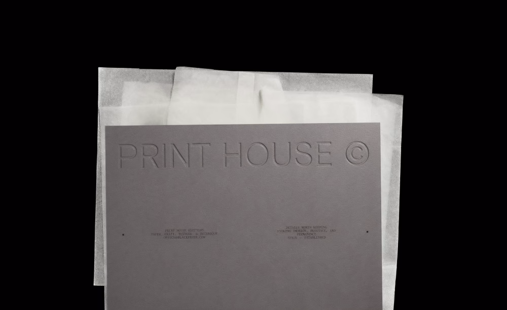 Tone-on-tone Print House wordmark on grey card over glassine sheets, Black Paper identity by DOMINGO.