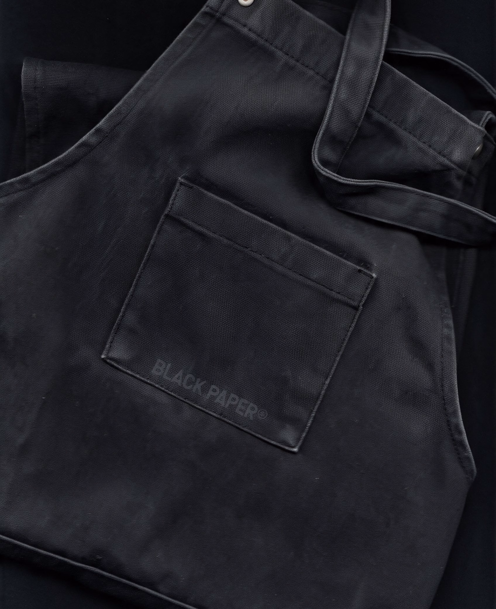 Black apron with a tone-on-tone Black Paper logo on the pocket, DOMINGO. print house merchandise