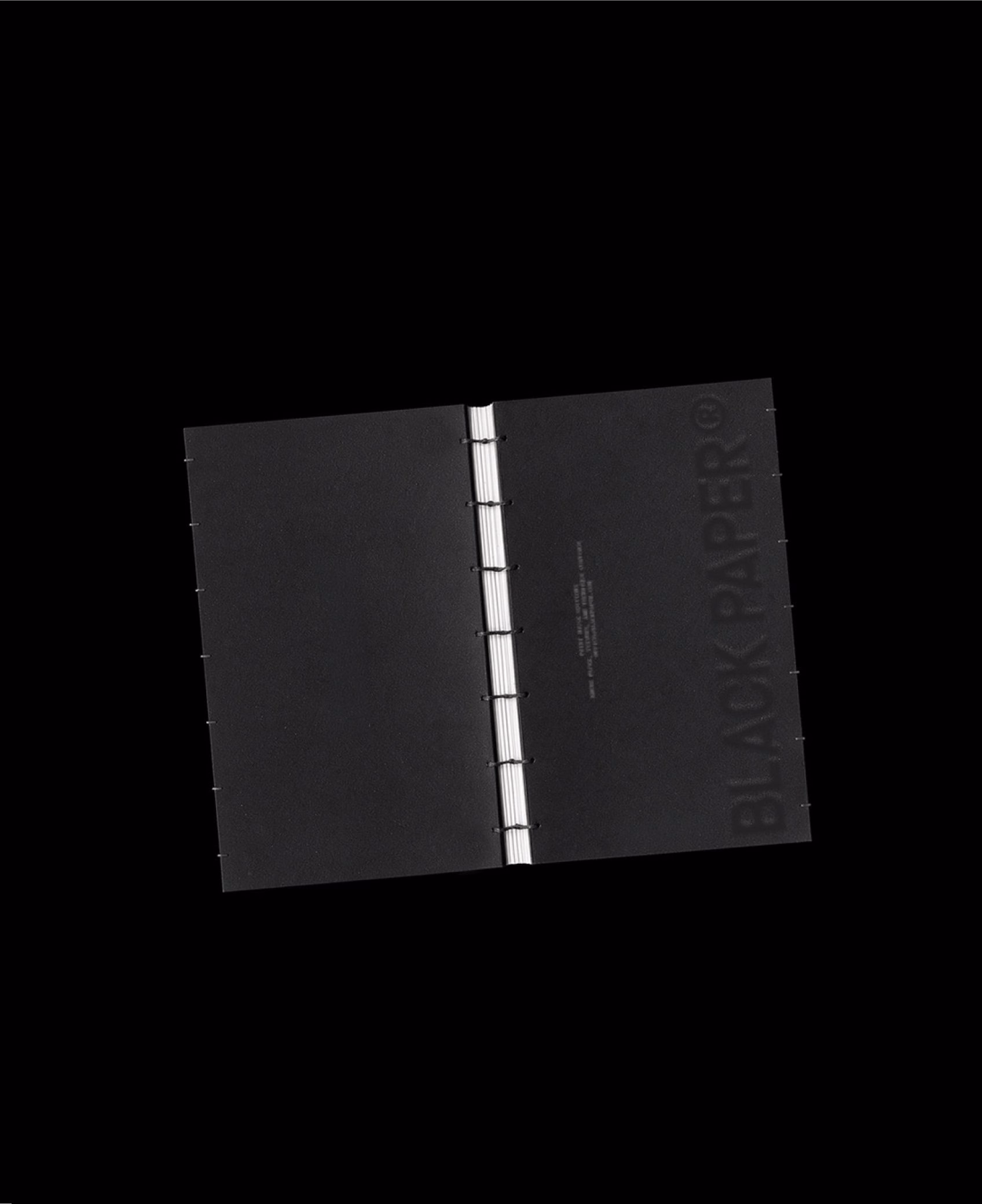 Black bound document with a white binding strip, Black Paper print house identity by DOMINGO.