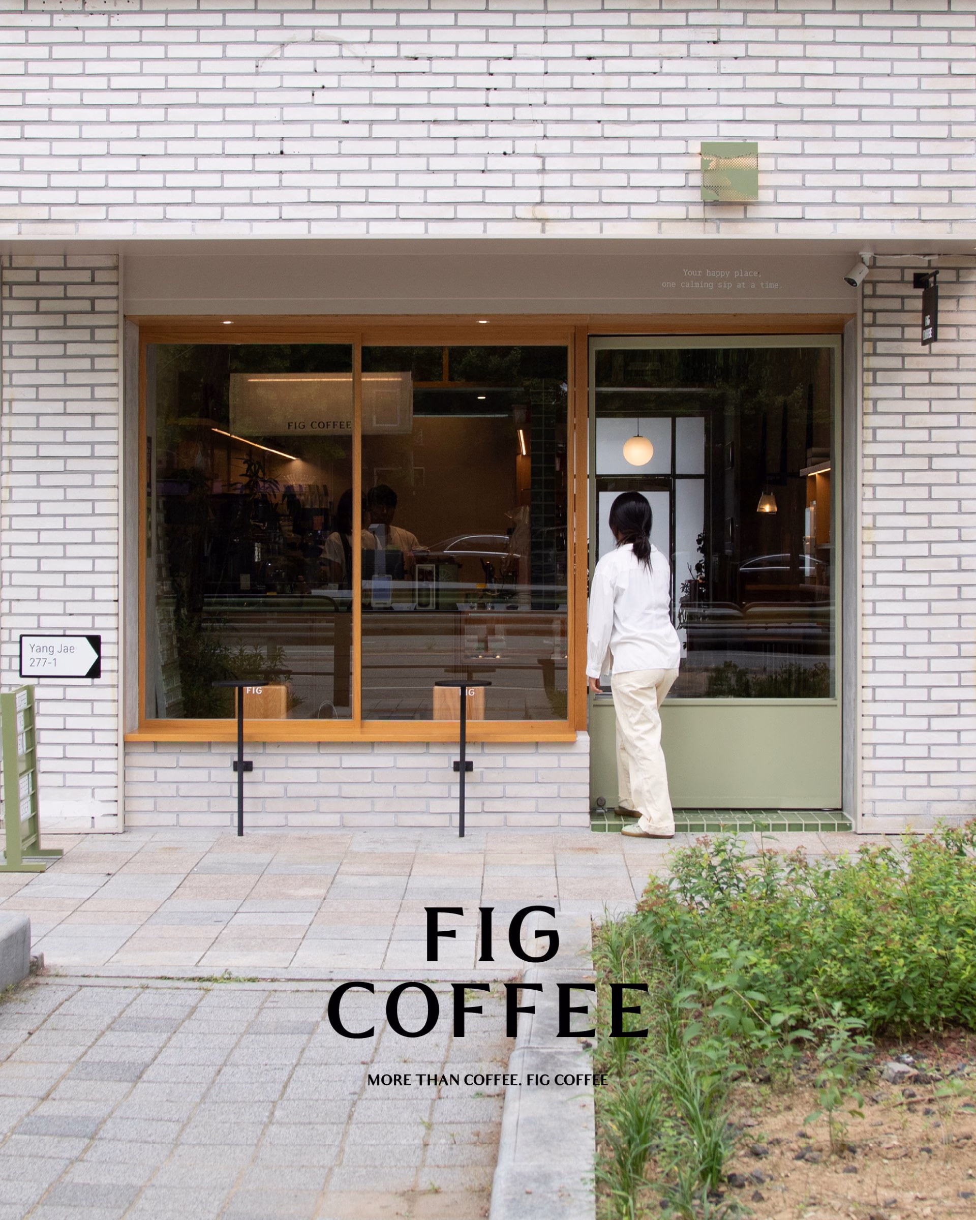 A person in a white outfit approaches the glass entrance of Fig Coffee, surrounded by a green gradient and brick walls.
