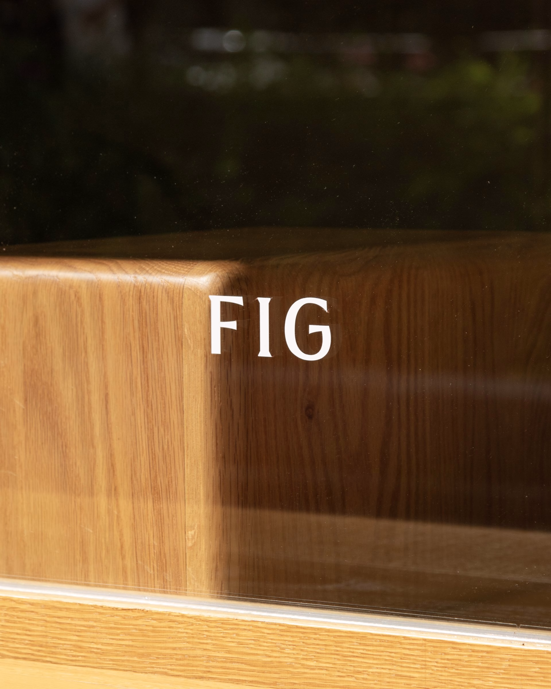 The word "FIG" is displayed in bold white typographic lettering on a wooden surface with warm tones.