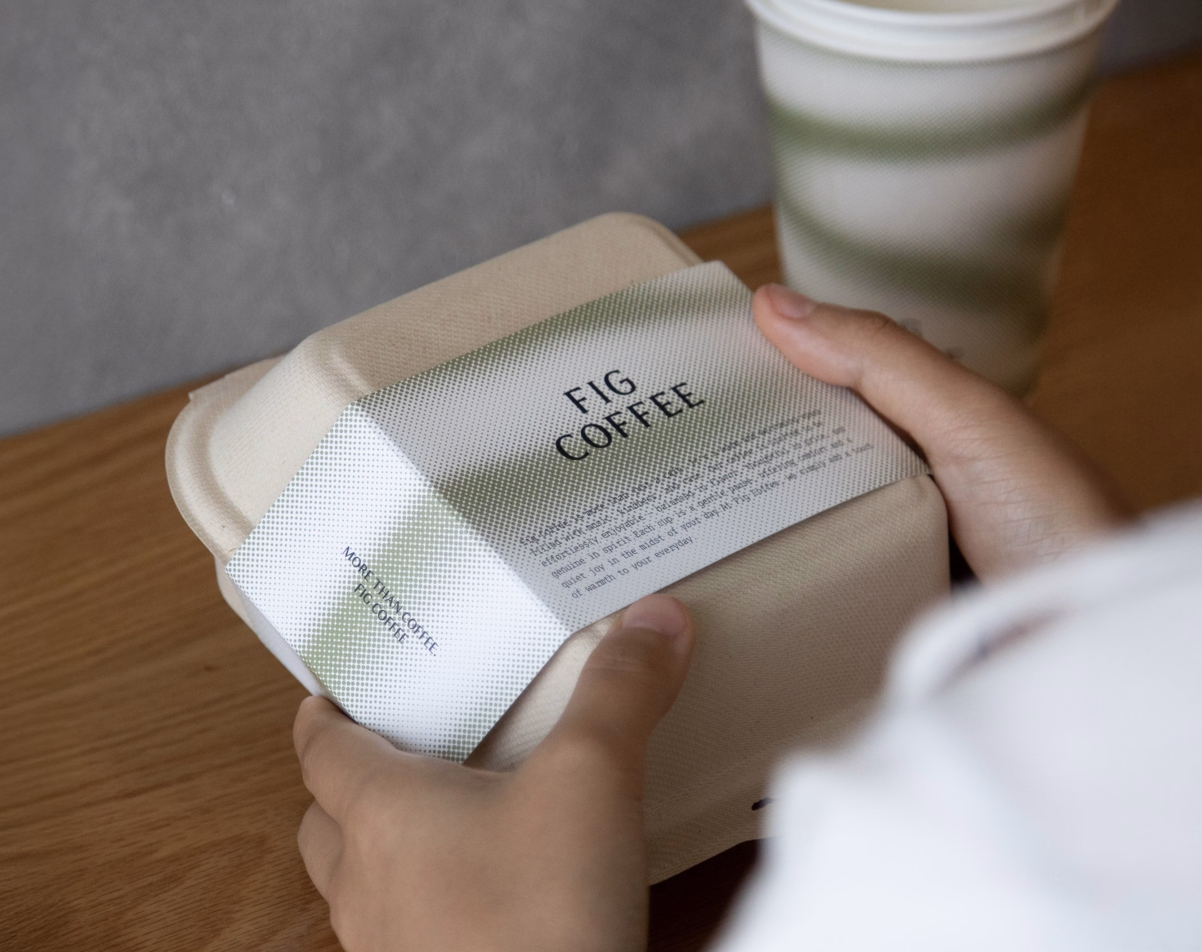 Hands opening a Fig Coffee pastry box with a green gradient wrap