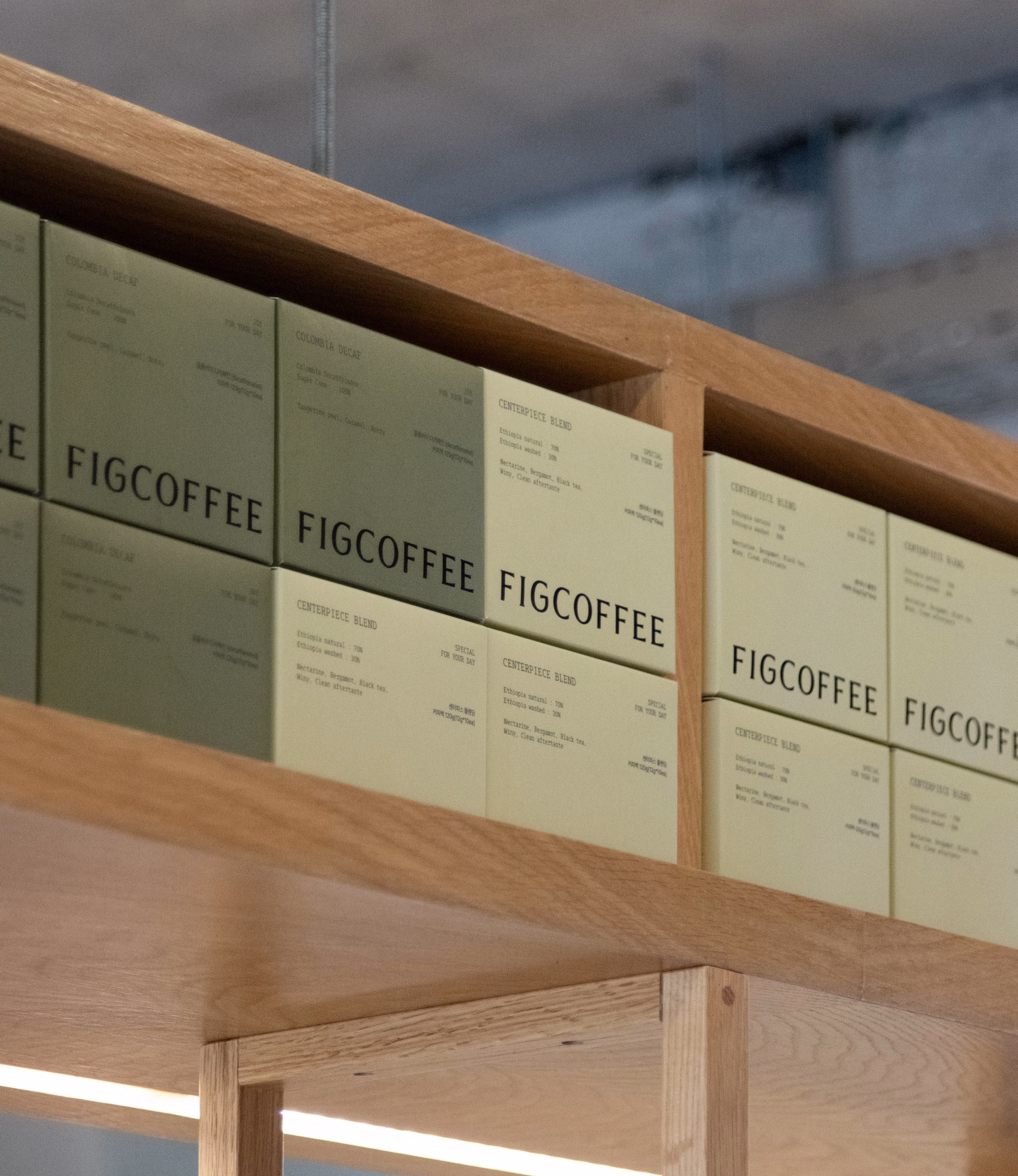 Green FIGCOFFEE boxes stacked on wooden shelves, retail packaging