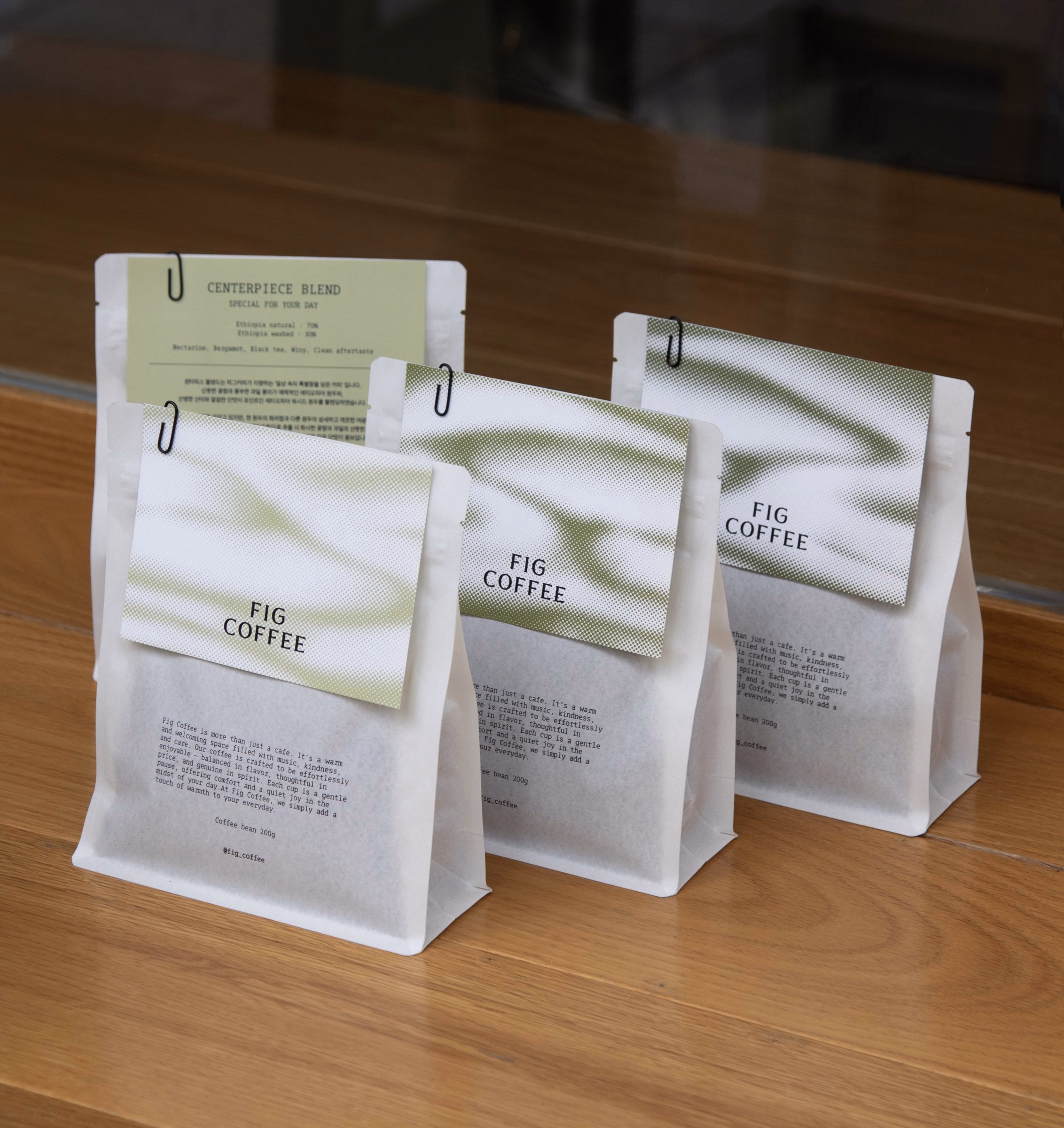White Fig Coffee bean bags with green gradient pattern lined up on a counter