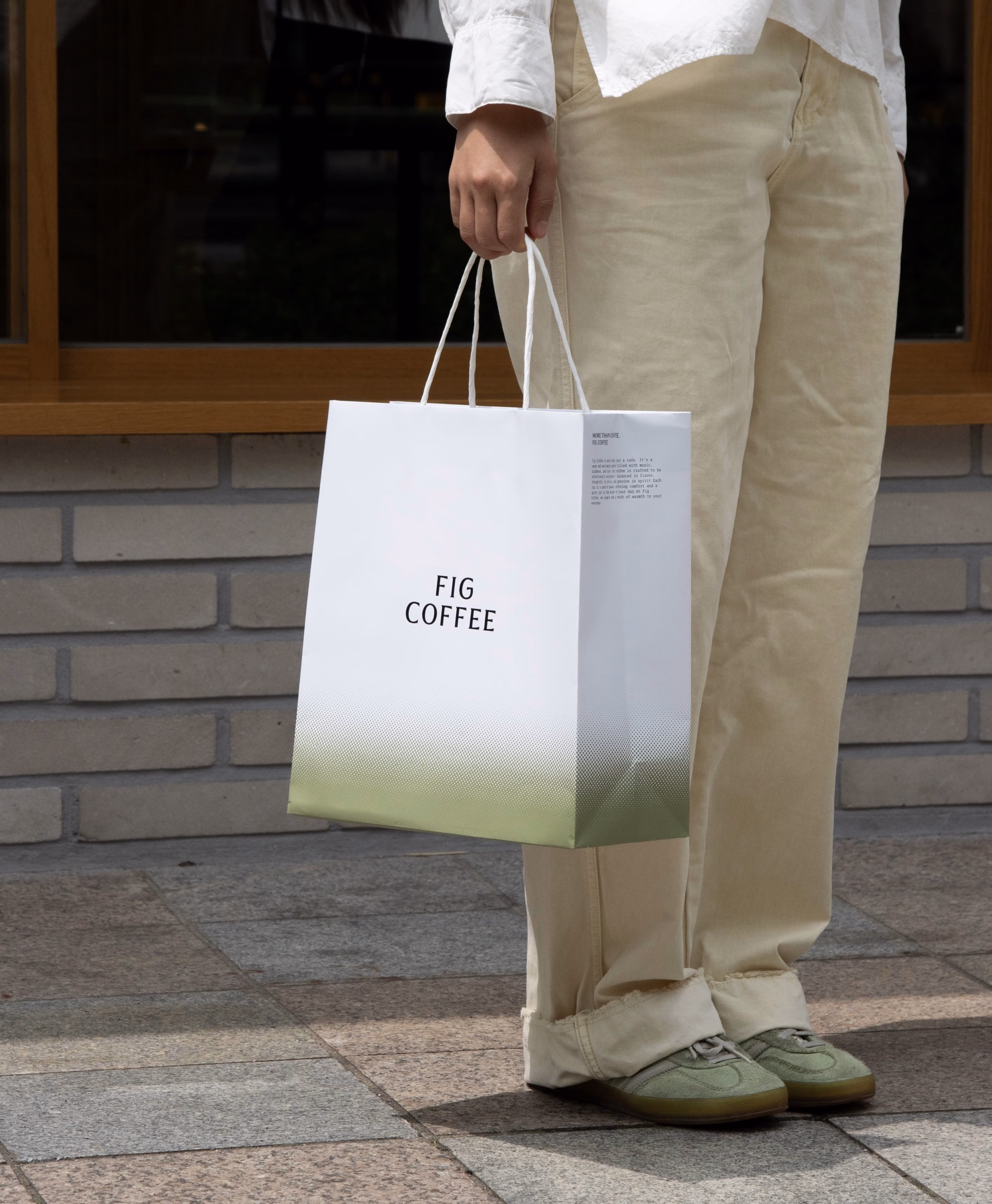 Customer carrying a white Fig Coffee shopping bag with a green gradient band