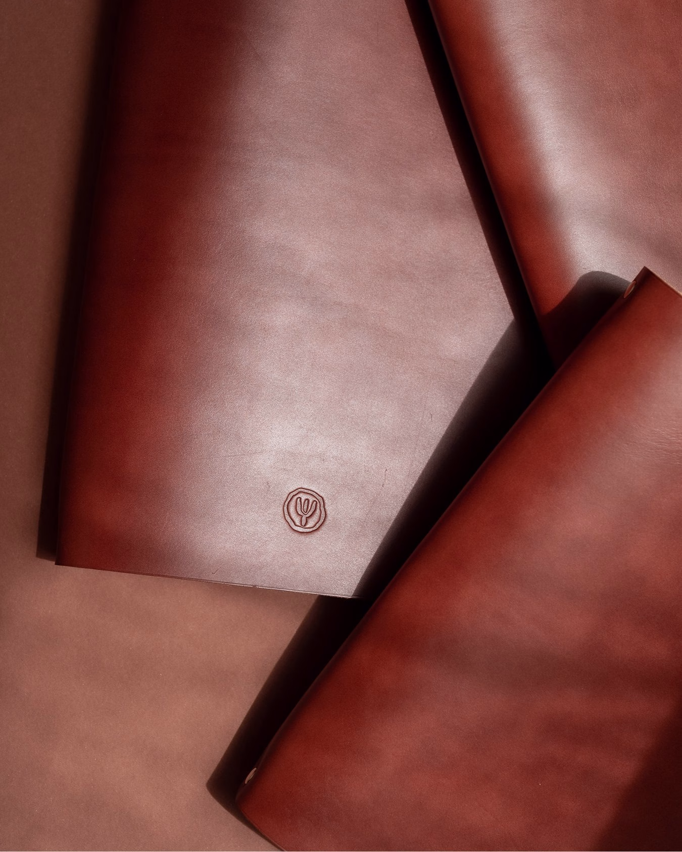 Brown leather pieces featuring a circular embossed logo, showcasing the elegant simplicity of the Relais du Castelet branding.