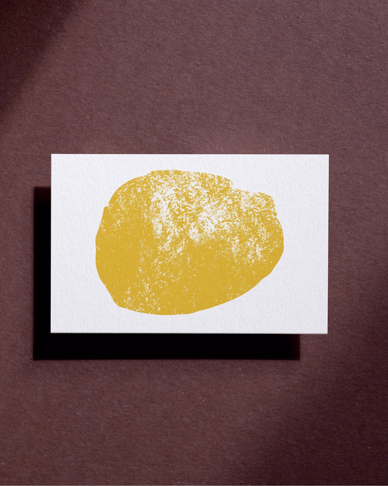 A textured yellow fertility symbol on a white card, set against a dark brown background, reflects brand identity design.