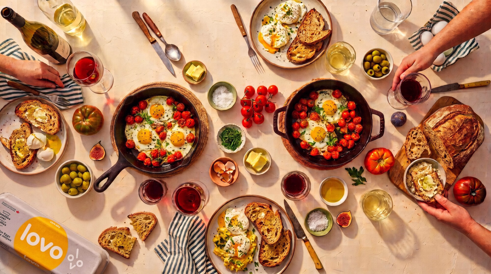 A vibrant brunch spread featuring sunny-side-up eggs, fresh tomatoes, and artisanal bread, with LOVO branding visible.